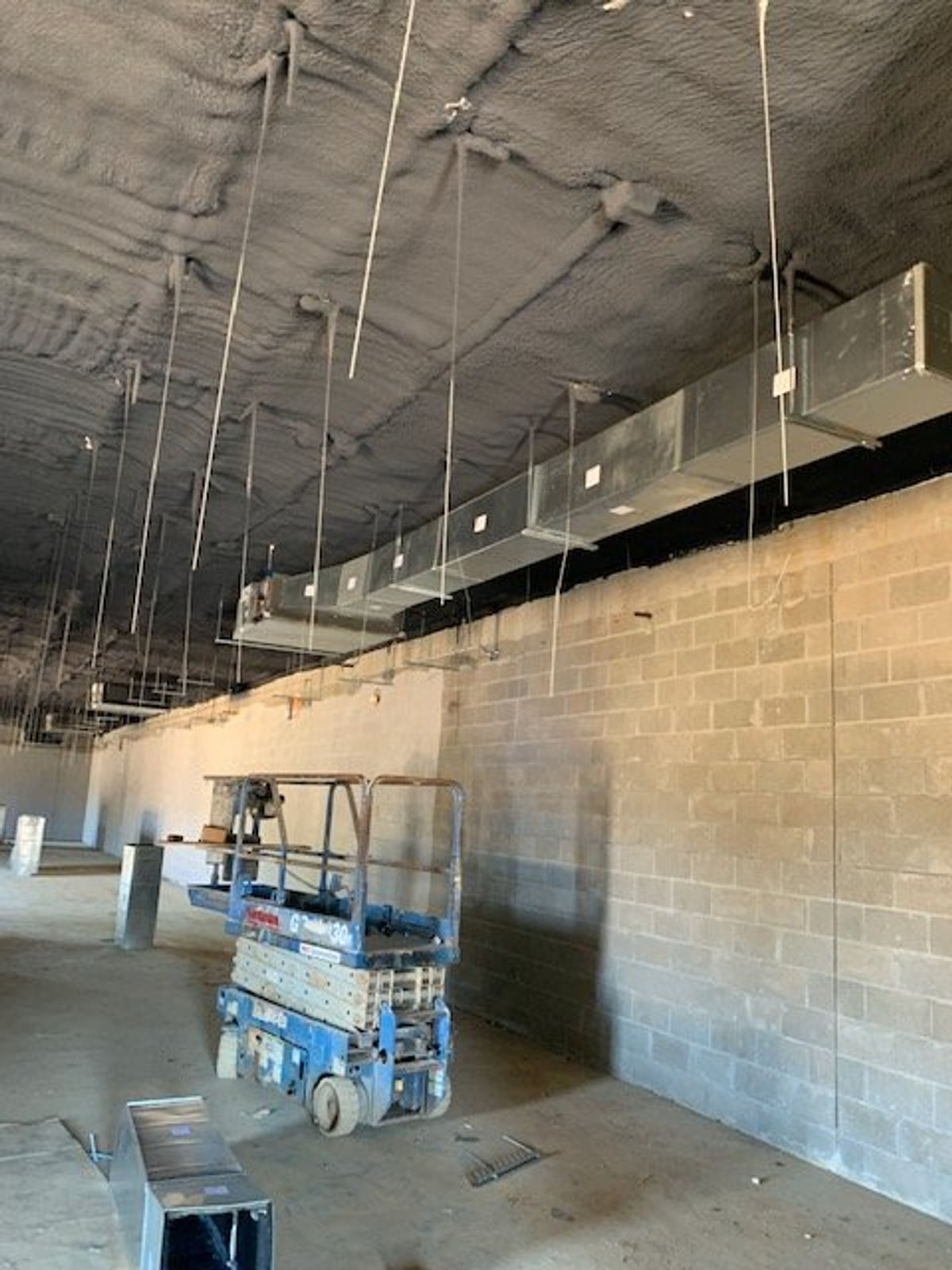 Exposed commercial ductwork suspended from the ceiling of a building under construction.