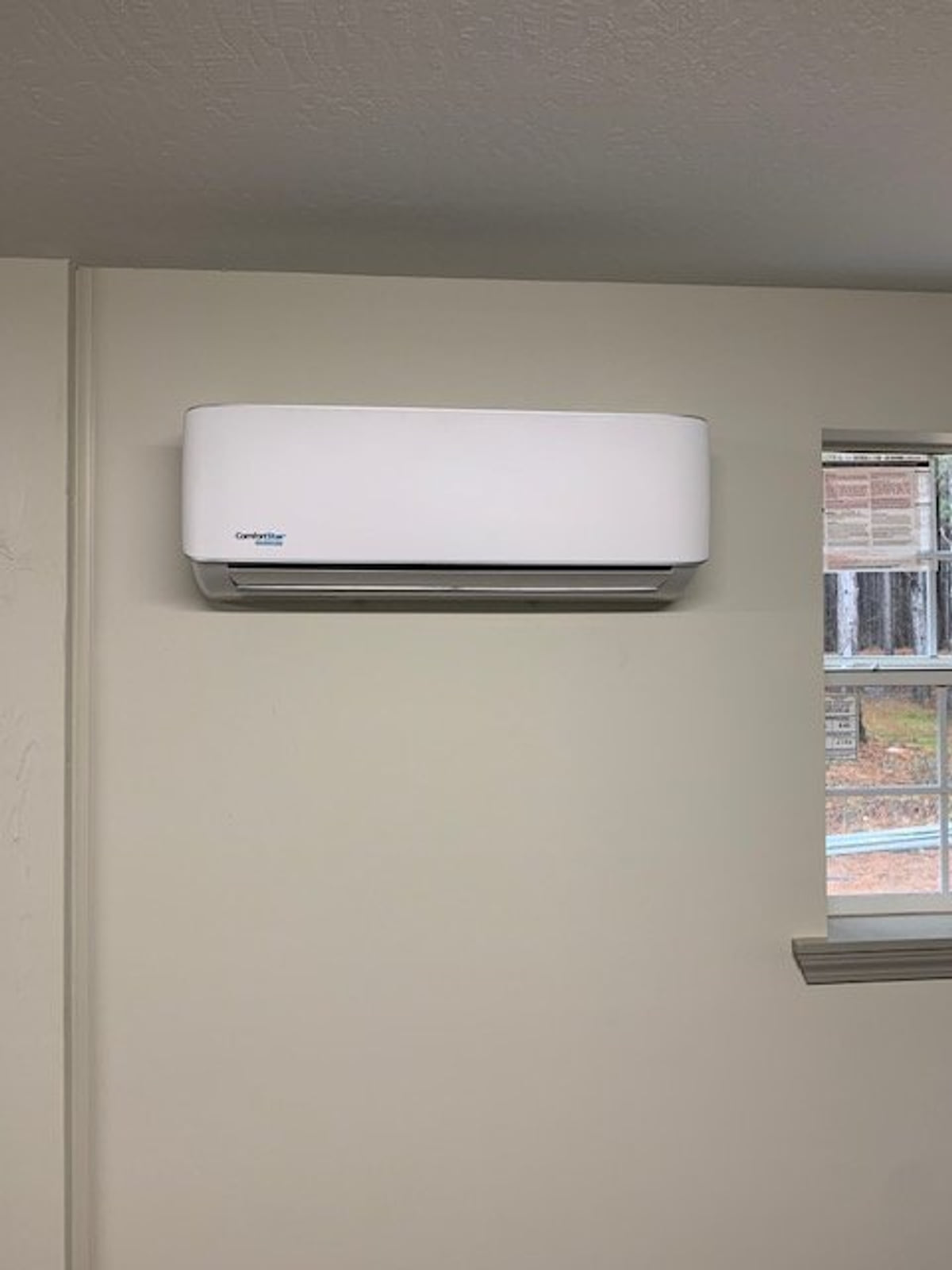 Indoor mini-split unit mounted near a window.