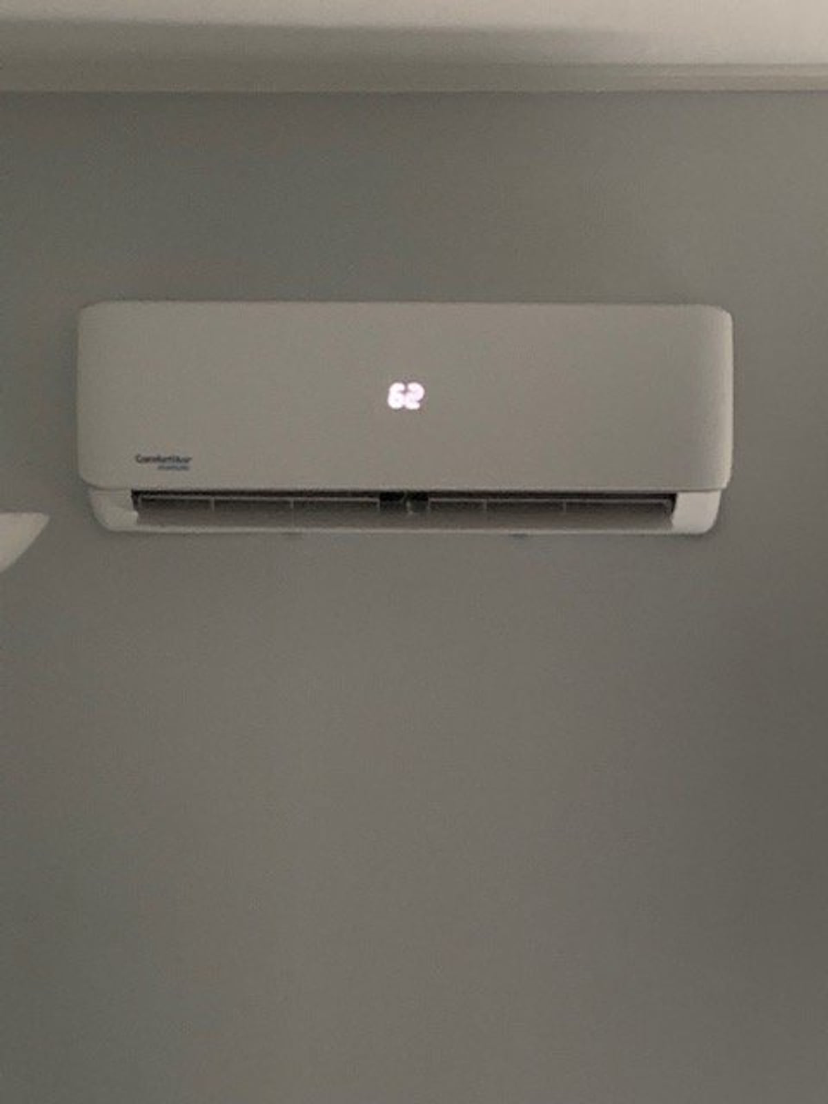 Wall-mounted indoor mini-split unit centered on a gray interior wall.